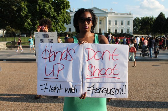 A woman holds up a sign at a protest in Ferguson, Missouri. Image Courtesy: Elvert Barnes, Flickr 